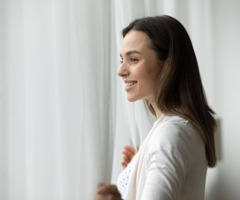 woman smiling while looking out of a window